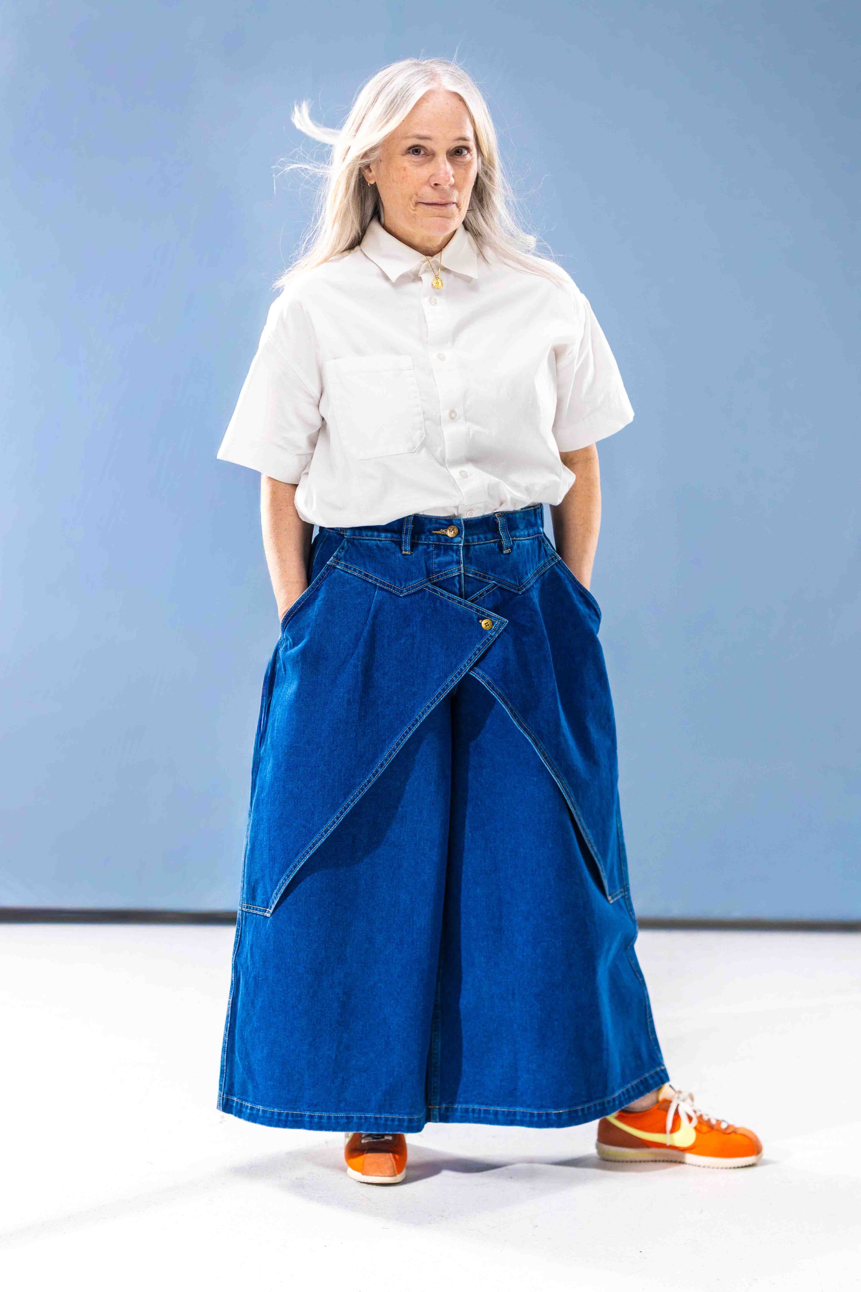 Person wearing a white shirt and blue denim pants against a light blue background